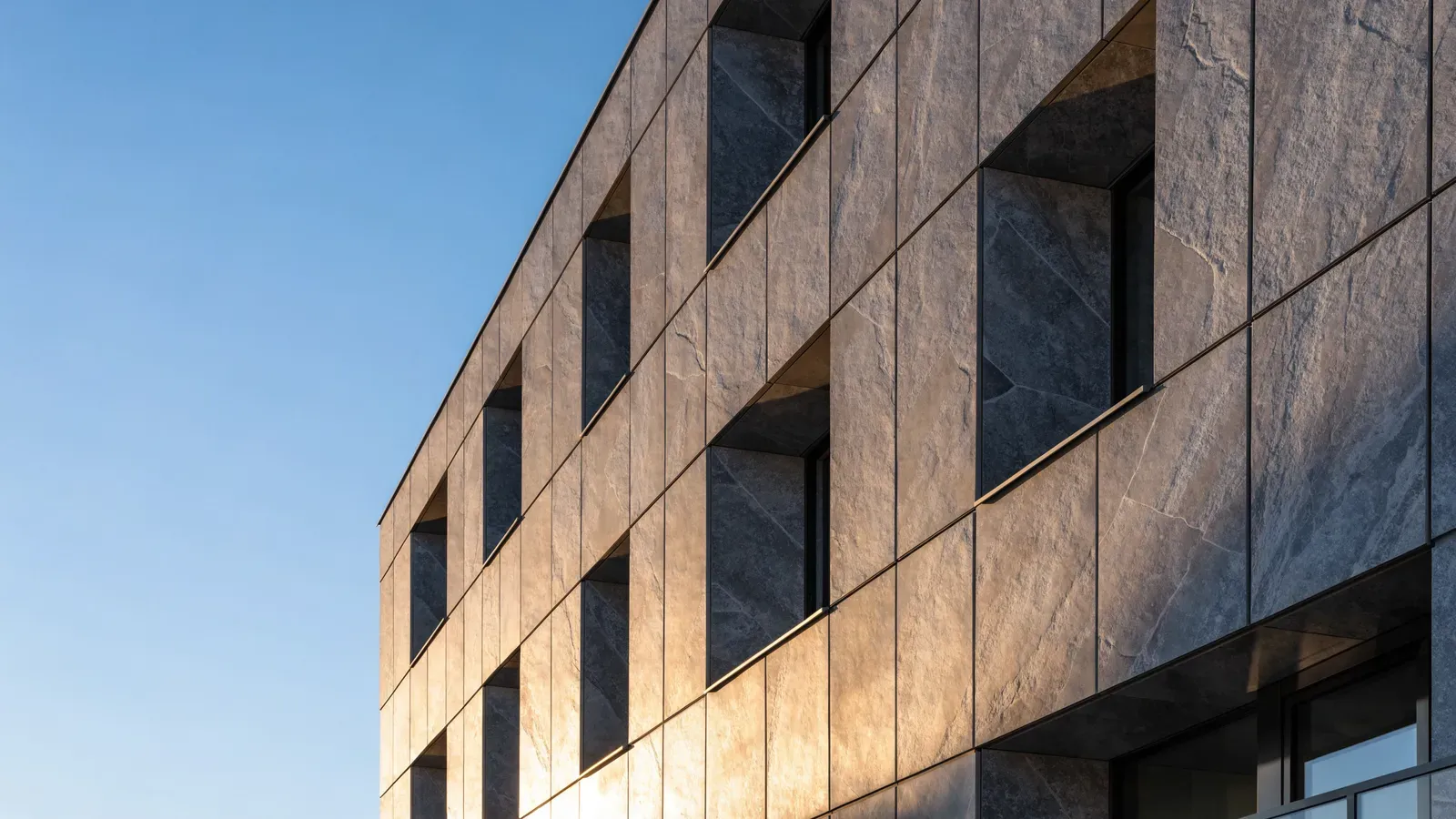 Edificio con fachada ventilada de porcelánico de gran formato en tono gris piedra